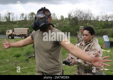 Un soldato della Guardia Nazionale di New York con la 222nd Chemical Company, 104th battaglione della polizia militare esegue un esercizio di decontaminazione a Fort Indiantown Gap il 14 maggio. Un altro saldatore rimuove con attenzione la maschera a gas per la decontaminazione degli ingranaggi. Foto Stock