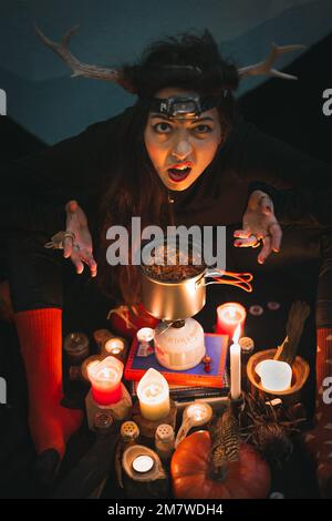 Primo piano donna sciamano con corna grimacing sopra vaso ritratto Foto Stock