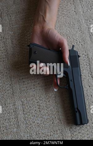 Primo piano di una mano di una donna che si posa sul pavimento senza stringere una pistola (pistola) Foto Stock