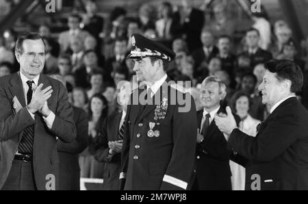 Il Vice Presidente George Bush (a sinistra), il Segretario della Difesa Caspar Weinberger (a destra) e gli ospiti onorati, si alzano e si battono durante la cerimonia di ritiro per GEN David C. Jones, presidente, Joint Chiefs of STAFF (centro). Base: Andrews Air Force base Stato: Maryland (MD) Paese: Stati Uniti d'America (USA) Foto Stock