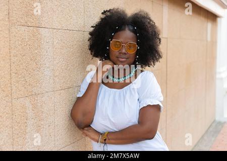 Donna afroamericana che guarda la macchina fotografica che indossa occhiali da sole Foto Stock