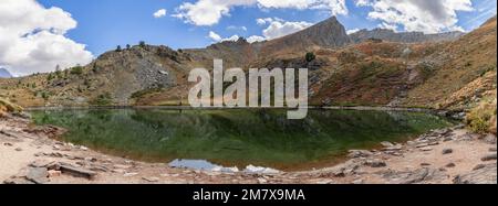 Favoloso panorama delle acque cristalline del Lago di Loie a 2354m m nella Valle di Bardoney con superbe vedute delle montagne circostanti sotto il cielo blu Foto Stock
