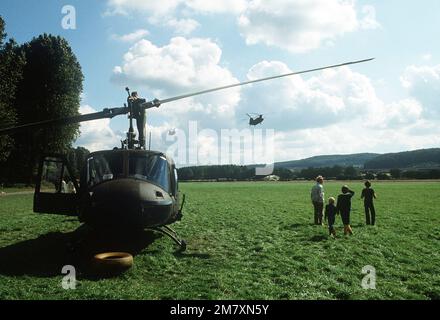 Un elicottero Iroquois UH-1N è parcheggiato durante l'esercizio Reforger '81. Due elicotteri CH-47 Chinook sono in volo sullo sfondo. Subject Operation/Series: REFORGER '81 base: Giessen Army Air Field Nazione: Germania Occidentale (FRG) Foto Stock