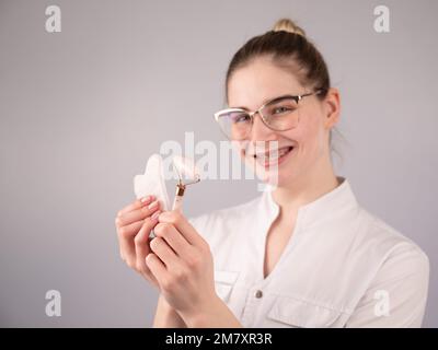 Medico estetista che tiene gouache raschietto e rullo. Foto Stock