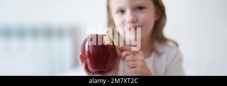 Ragazza bambino morde e mangia grande mela rossa Foto Stock