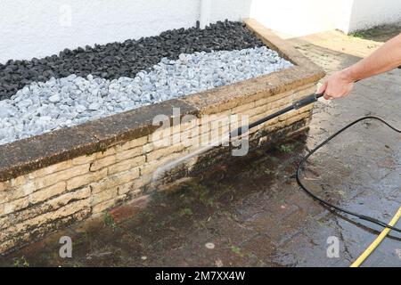 L'operatore spruzzando acqua pulisce la parete sporca con la pressione del getto d'acqua Foto Stock