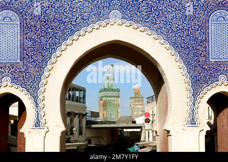 Il Bab Bou Jeloud è una recente aggiunta a Fes El Bali, essendo stato costruito intorno al 1913. Il minareto Medersa Bou Inania è incorniciato da questo imponente gat Foto Stock