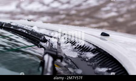 Le spazzole dei tergicristalli si chiudono con il ghiaccio su sfondo invernale sfocato Foto Stock