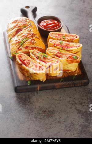 Pizza calda appena sfornata stromboli rotolo con salsiccia e formaggio primo piano su un asse di legno sul tavolo. Verticale Foto Stock