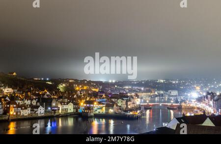 Una vista aerea del porto illuminato di Whitby in una serata nebbiosa nello Yorkshire, Inghilterra Foto Stock