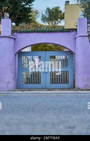 Una porta metallica grigia con parete viola in una strada marocchina Foto Stock