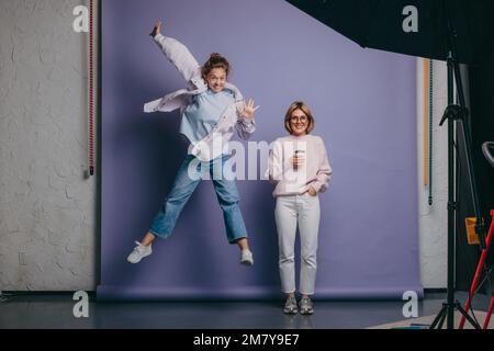 Ritratto di due ragazze in piedi in studio e in posa in diverse posizioni. Amiche felici insieme. Foto Stock