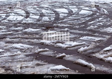 Sudicio tracciato di pneumatici auto su neve sciogliente su asfalto della strada Foto Stock