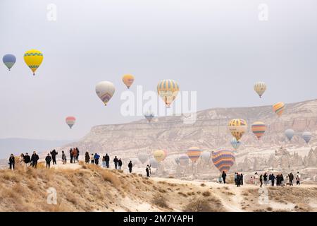 Vista mozzafiato alcune persone ammirano alcune mongolfiere che volano sullo splendido paesaggio della Cappadocia. Foto Stock