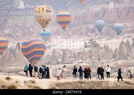 Vista mozzafiato alcune persone ammirano alcune mongolfiere che volano sullo splendido paesaggio della Cappadocia. Foto Stock