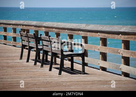 Panchine di fronte all'oceano presso il molo di Ventura, California Foto Stock