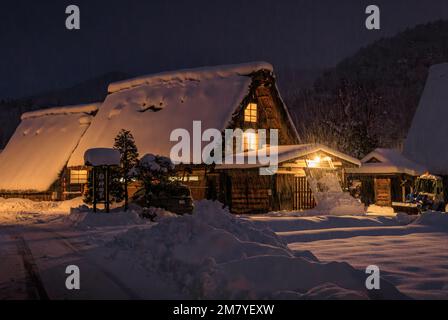 La neve cade sulla tradizionale casa giapponese gassho-zukuri di notte Foto Stock