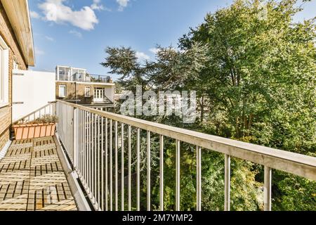 un balcone con ringhiere bianche e alberi verdi davanti - immagine è stata presa dalla terrazza sul tetto di un appartamento Foto Stock