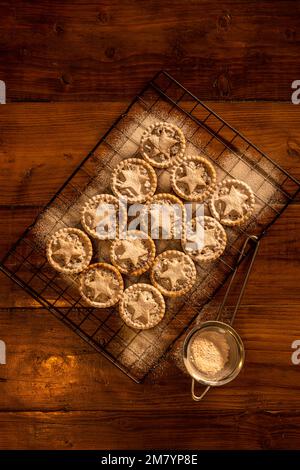 Piatto mettere mince torte sormontate con stelle di pasticceria, spolverato con zucchero a velo su sfondo di legno scuro: Natale casa cottura. Foto Stock