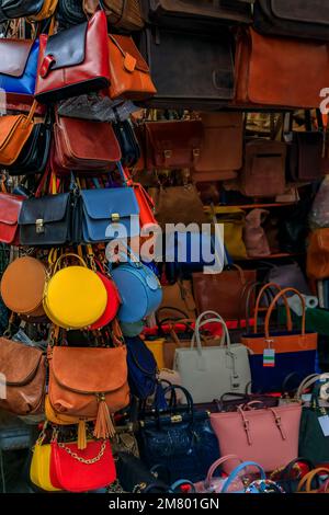 Prodotti in pelle colorata, borse, zaini e cinture in mostra presso un negozio di strada nel mercato Centrale di Firenze Foto Stock