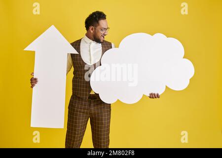 Un uomo entusiasta che tiene una grande freccia sulla carta e il cloud, concetto di servizio di storage Foto Stock