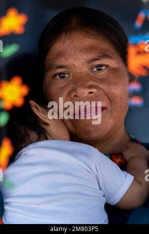 donna artigiana indigena con la sua figlia neonato con il suo artigianato appeso ai suoi lati Foto Stock