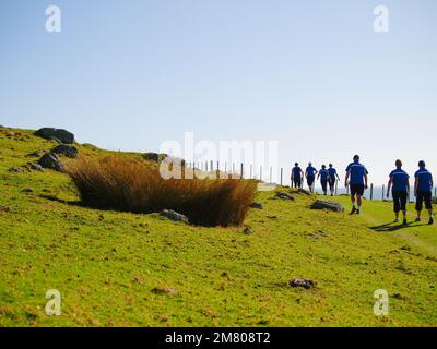 Tauranga Nuova Zelanda - Aprile 30 2010; Editorial-Walking gruppo in silhouette indossando camicie blu a piedi via sul lato Monte Maunganui Foto Stock