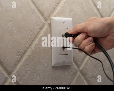 Elettricista maschio che collega il cavo coassiale alla presa a muro. Connessione coassiale per TV, internet a banda larga ad alta velocità e telefono a linea terrestre. Tel Foto Stock