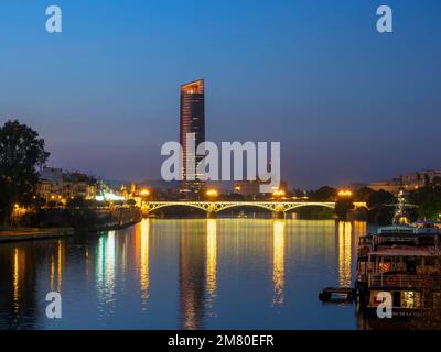 Vista notturna del fiume Guadalquivir a Siviglia con grattacieli moderni sullo sfondo. Foto Stock