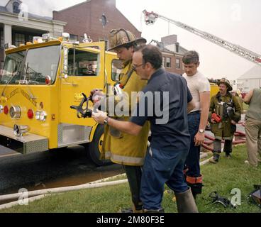 Un vigile del fuoco del Dipartimento dei vigili del fuoco del Distretto di Columbia regola una maschera protettiva mentre lavora con il Dipartimento dei vigili del fuoco del Distretto Navale di Washington per spegnere un incendio presso l'Enterprise Hall, Anacostia Naval Station. (Immagine substandard). Base: Washington Stato: District of Columbia (DC) Nazione: Stati Uniti d'America (USA) Foto Stock