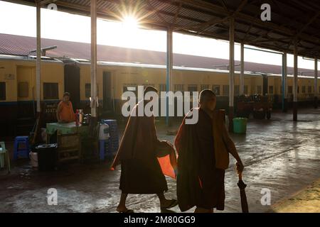 Myanmar vita quotidiana, alba. I monaci camminano attraverso una stazione ferroviaria di myanmar. A sud di Yangon, Myanmar Foto Stock