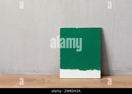 Campionatore di colore verde sulla parete in gesso bianco. Scelta del colore della pittura della parete durante il rinnovo della casa. Foto Stock