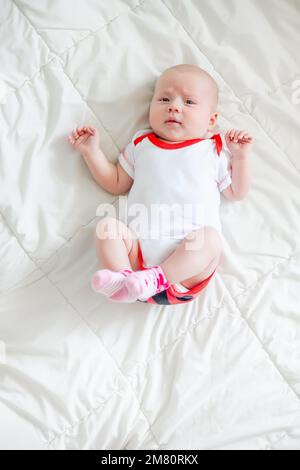 Un bambino piccolo si trova spingendo le gambe sul pancino. Coliche o crampi allo stomaco nei bambini di età inferiore a 3 mesi. Malattie di infanti Foto Stock