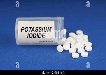 Il concetto di farmacologia e salute. Su una superficie blu ci sono pillole e un vaso polveroso con l'iscrizione - ioduro di potassio Foto Stock
