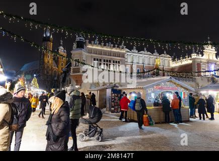 Mercato di Natale di Cracovia di notte, la gente nella piazza del mercato principale con il Coperto di stoffa nella neve d'inverno, Cracovia Polonia Europa Foto Stock