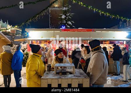 Mercato di Natale di Cracovia - persone che parlano, bevono e si divertono di notte, Piazza del mercato principale di Cracovia, Cracovia, Polonia Europa Foto Stock