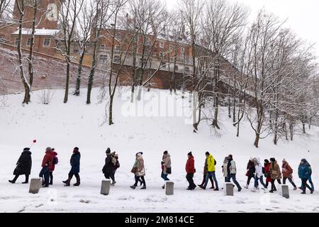 Tour guidato di Cracovia - una guida turistica con bandiera che conduce un gruppo di persone che camminano in fila nella neve invernale, il Castello di Wawel, la Città Vecchia di Cracovia, Cracovia Polonia Foto Stock