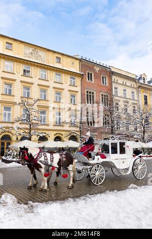 Turismo in Polonia; cavalli e carrozza in attesa di turisti; Piazza del mercato principale di Cracovia nella neve d'inverno a Natale; Città Vecchia di Cracovia, Cracovia Polonia Europa Foto Stock