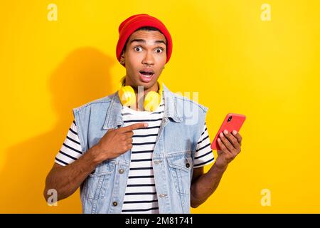 Foto di un utente stupito dimostrare la qualità del telefono consigliato dispositivo moderno isolato su sfondo giallo Foto Stock