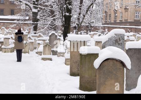 Quartiere ebraico di Cracovia - un visitatore nel cimitero della Sinagoga di Remuh nella neve d'inverno, Cracovia, Polonia Europa Foto Stock
