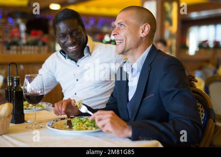 Due allegri amici maschili a cena al ristorante Foto Stock
