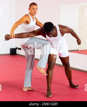 Due uomini adault che praticano le tecniche di autodifesa in palestra sportiva Foto Stock