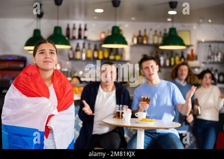 Triste ragazza con amici sconvolta dalla perdita della sua squadra preferita dei Paesi Bassi Foto Stock