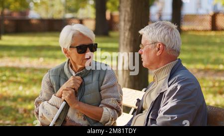 Donna anziana cieca con occhiali da sole scuri con il marito nel parco. Foto di alta qualità Foto Stock