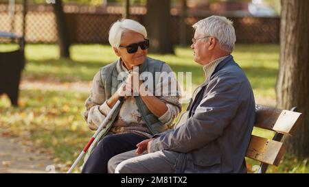 Donna anziana cieca con il marito seduto su una panchina nel parco. Foto di alta qualità Foto Stock
