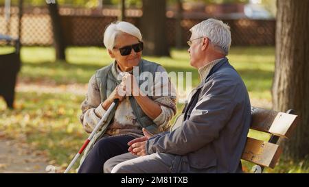 Donna anziana cieca con occhiali da sole scuri con il marito nel parco. Foto di alta qualità Foto Stock