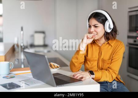 Donna araba stressata che soffre problemi mentre lavora con computer portatile a casa Foto Stock