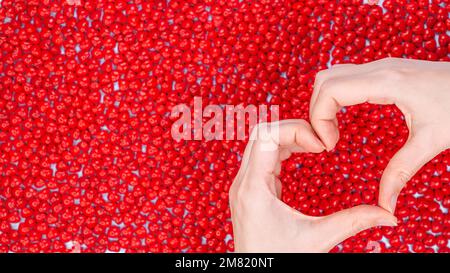 Mani di donna che fanno forma di cuore su sfondo rosso caramella. Cuore dalle mani. Concetto di San Valentino. Simbolo e forma del cuore creati dalle mani. pe rosso Foto Stock