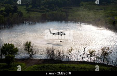 Un equipaggio di Bravo Company, 2/147th Battaglione di elicottero d'assalto, abbassare un secchio di bambi per raccogliere l'acqua durante l'addestramento del secchio d'acqua al Wendhell H. Ford Regional Training Center di Greenville, Ky., 19 luglio 2021. L'addestramento del secchio d'acqua fornisce agli equipaggi dell'elicottero un modo sicuro per innaffiare rapidamente gli incendi boschivi e selvaggi per supportare i vigili del fuoco locali quando chiamati. (STATI UNITI Foto della Guardia Nazionale militare di SPC. Danielle Sturgill) Foto Stock