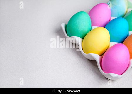 Uova pasquali pastello giacenti su tavola bianca. Decorazione tradizionale Foto Stock